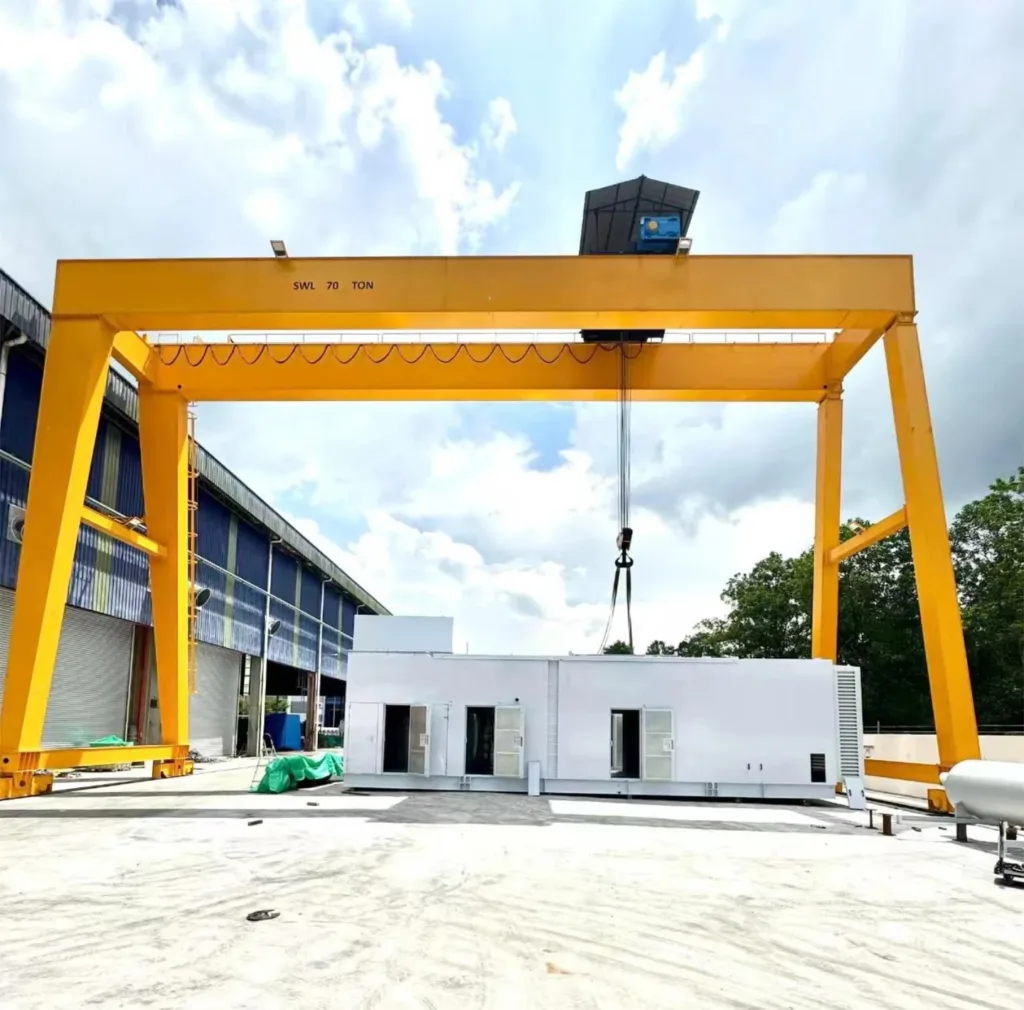 Double box-girder gantry crane lifting a large fabricated module beside a factory