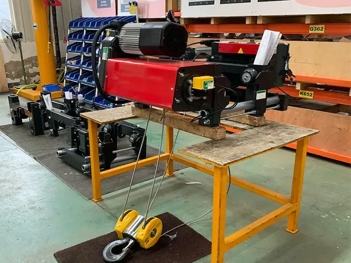 Low-headroom wire-rope hoist and compact trolley on a workshop assembly bench
