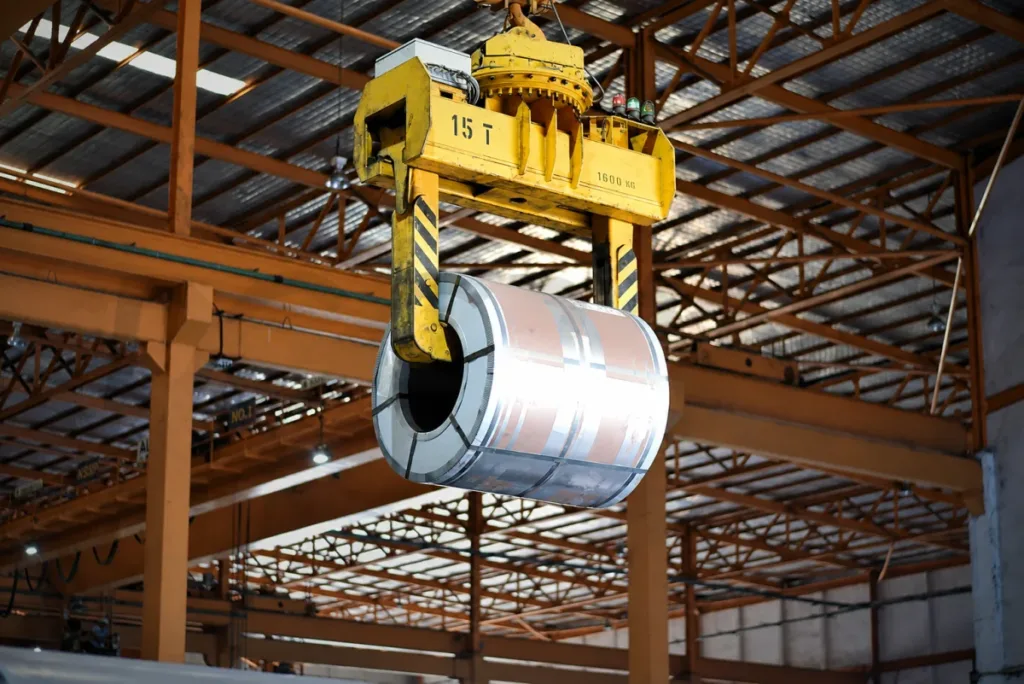 Coil tong carrying a horizontal-eye metal coil in a workshop