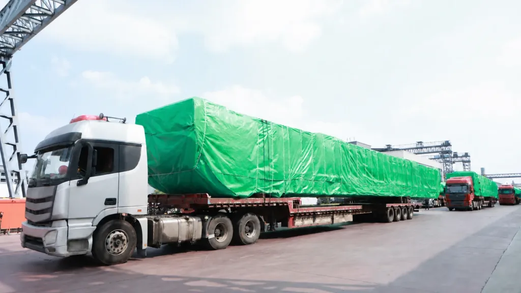 Wrapped crane loads secured on flatbed trucks in an outbound convoy