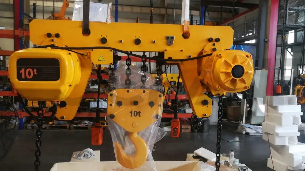 Completed high-capacity electric chain hoist and trolley with motor, chains and hook block on a factory floor