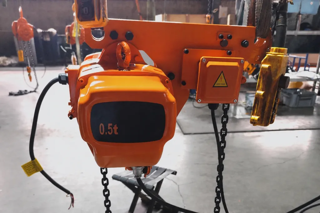 Fixed electric chain hoist during factory preparation with suspension, load chain and pendant visible