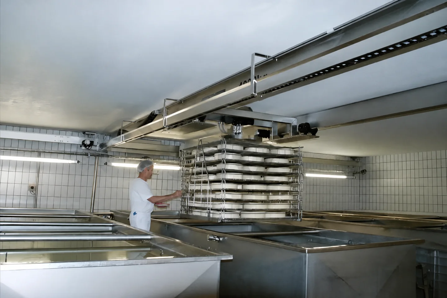 Double-girder cleanroom crane handling stacked trays above stainless process vats