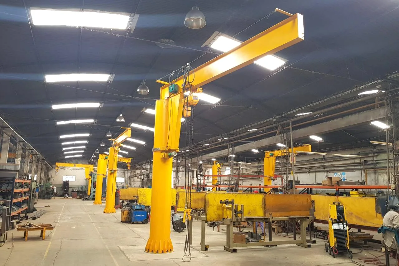 Multiple free-standing jib cranes serving work stations in an industrial workshop