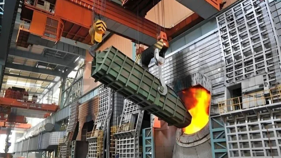 Metallurgical process crane tilting a charging vessel at a high-temperature furnace