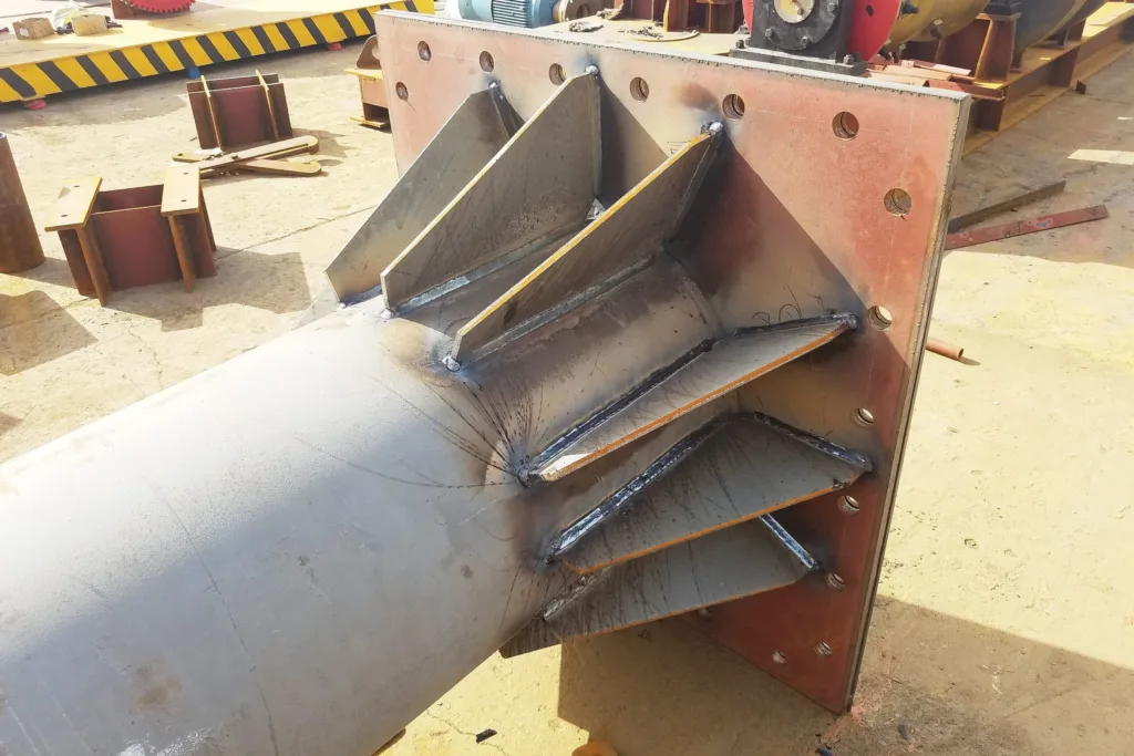 Fabricated jib crane mast base showing structural welds and foundation interface
