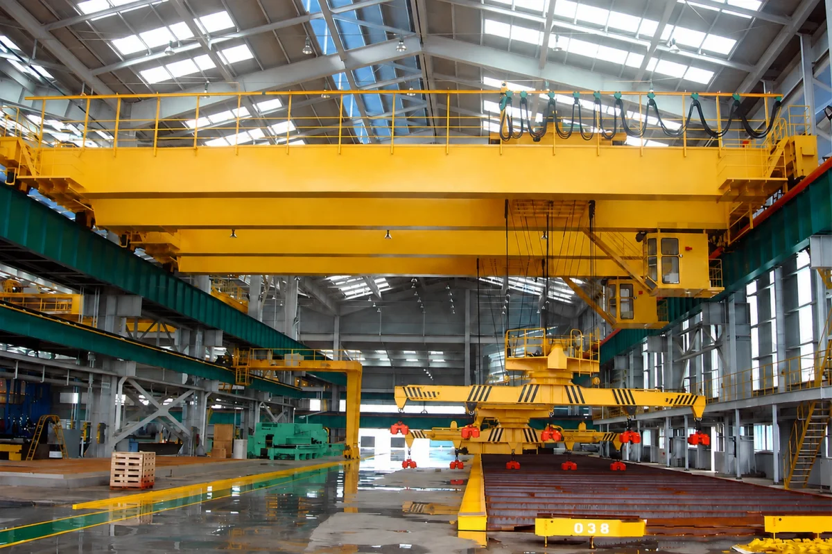 Overhead crane with a rotating lifting beam and multiple magnet units above long steel stock