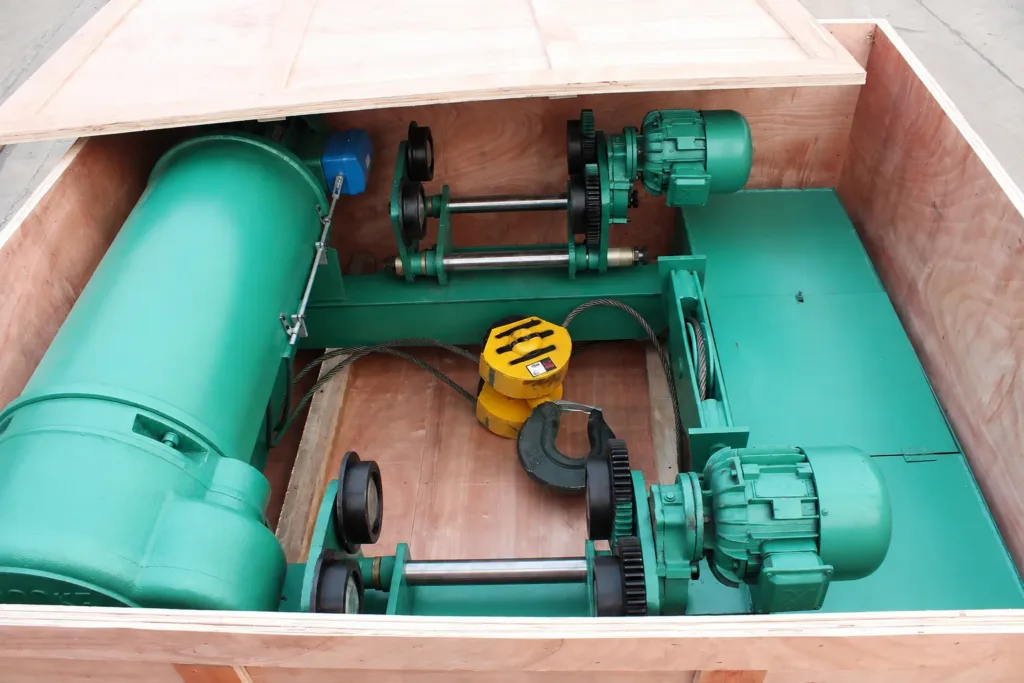 Low-headroom wire-rope hoist assembly showing the drum, rope, hook block, trolley wheels and travel drives