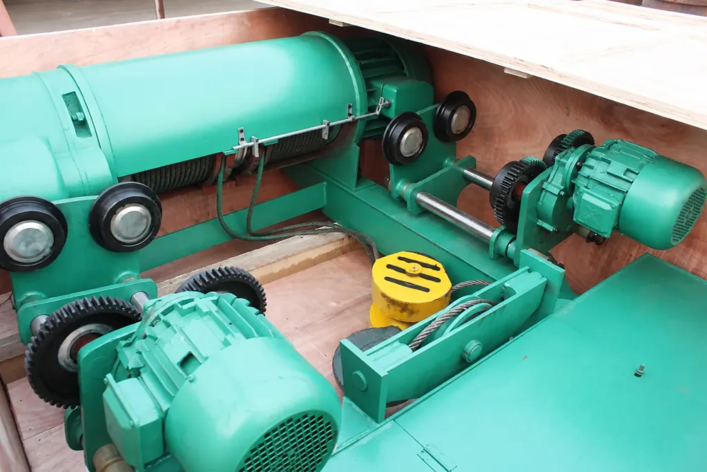 Low-headroom electric wire-rope hoist assembly showing the drum, trolley wheels and travel drive