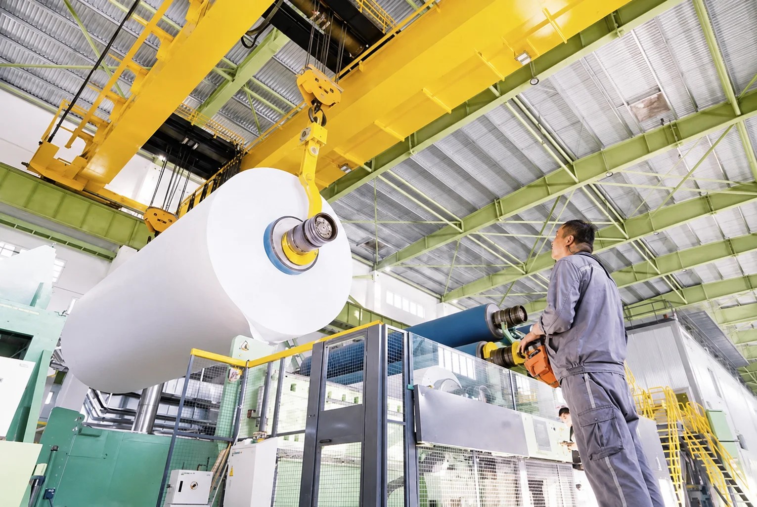 Overhead crane lifting a large parent paper roll at a paper machine