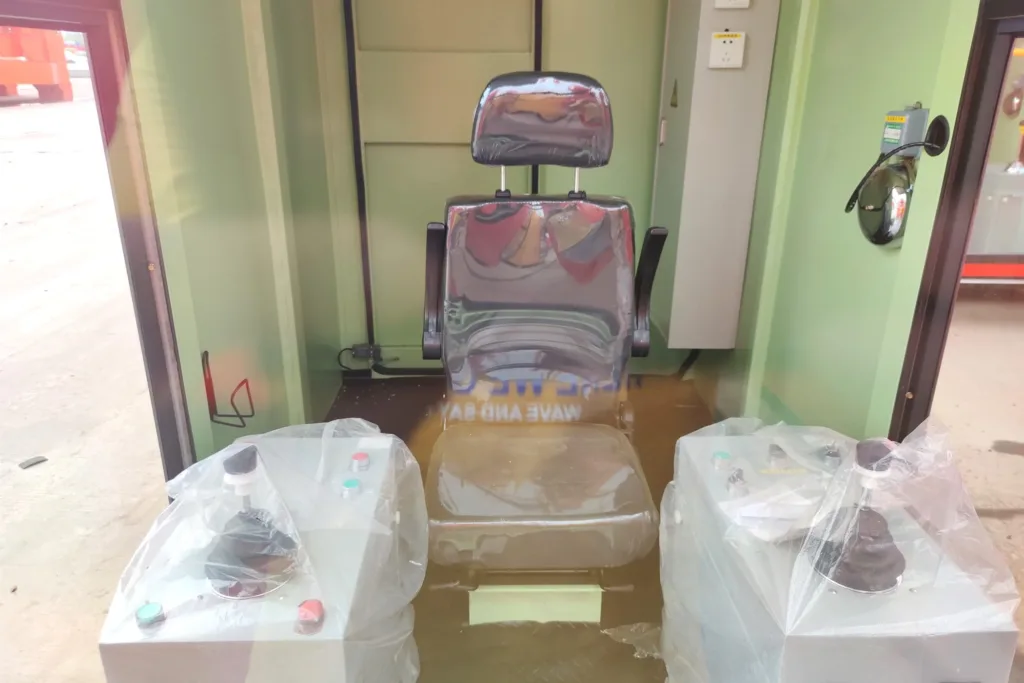 Seat and two joystick consoles inside a glazed crane cabin