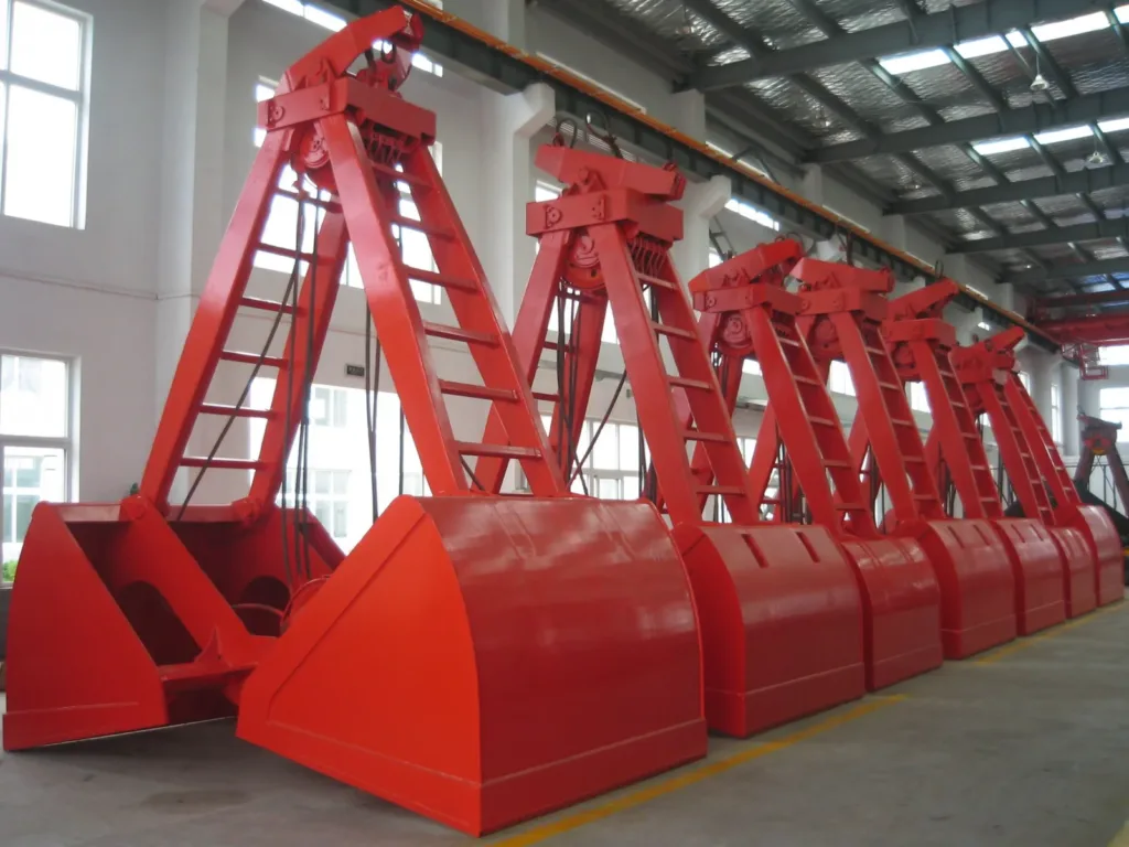 Red mechanical clamshell grabs with two shells and rope sheaves in a workshop