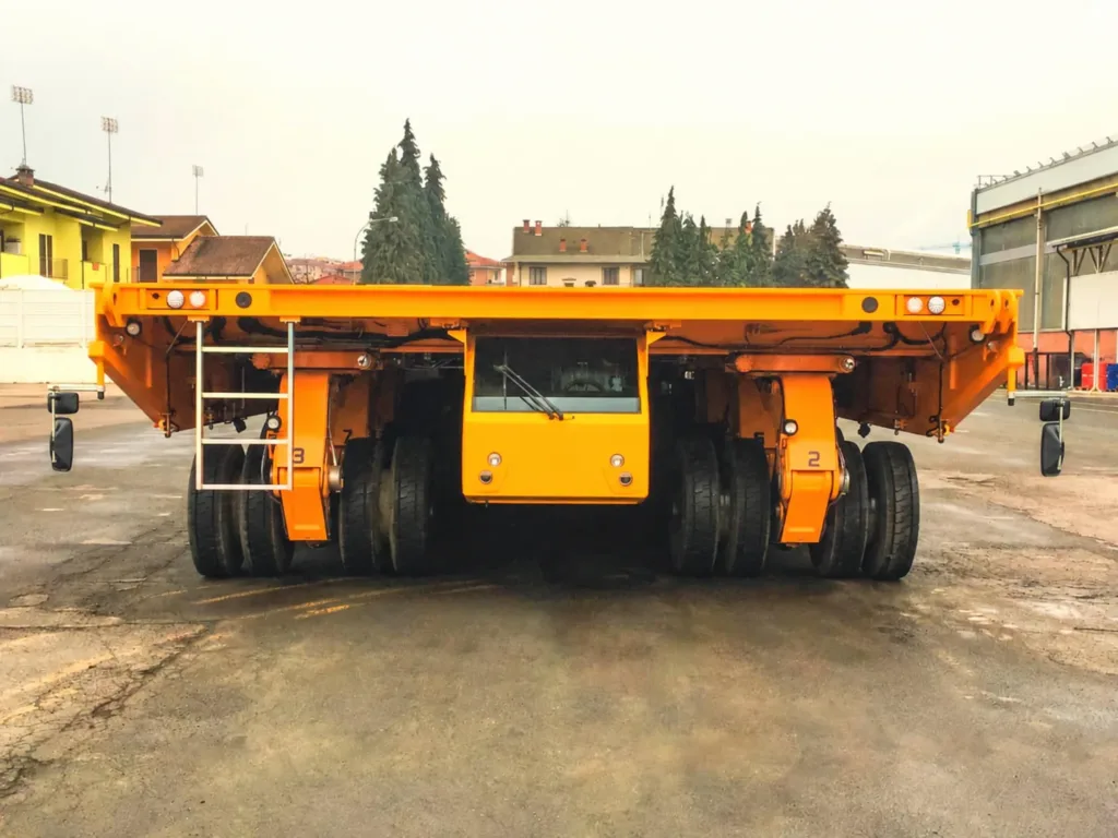 Front view of hydraulic platform transporter showing wheel units suspension links and cab below the deck