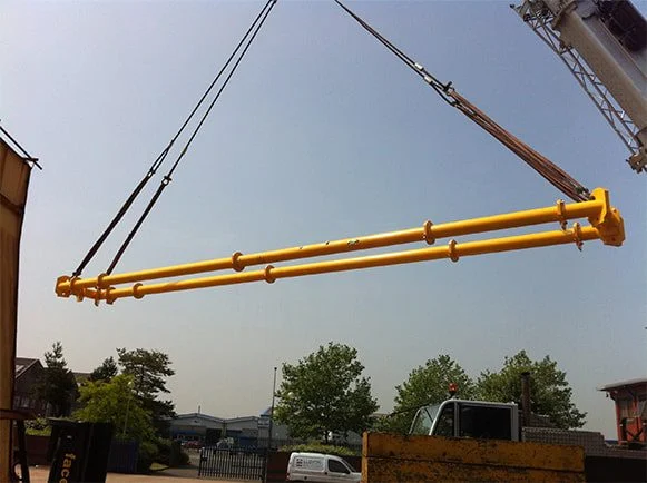 Yellow rectangular four-corner spreader frame suspended outdoors, without a load