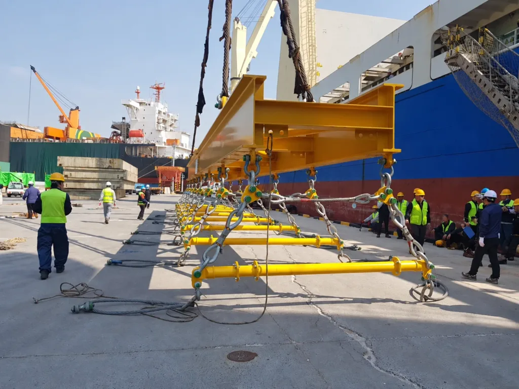 Close view of main lifting frame, upper ropes, connecting shackles and transverse spreaders resting near the ground