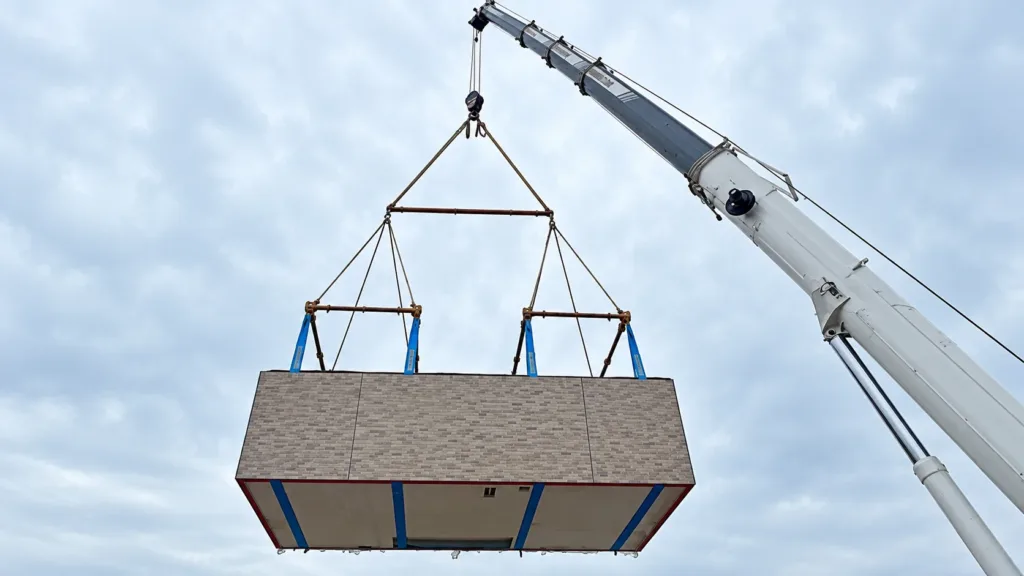 A main spreader beam suspends two smaller frames and slings supporting a rectangular building module