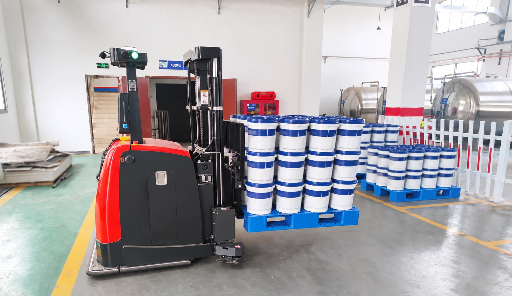 Autonomous forklift lifting a loaded pallet in a factory