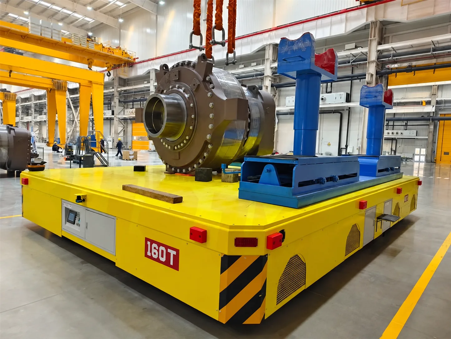 Yellow multiwheel transfer platform with an industrial assembly and blue support fixtures in a workshop