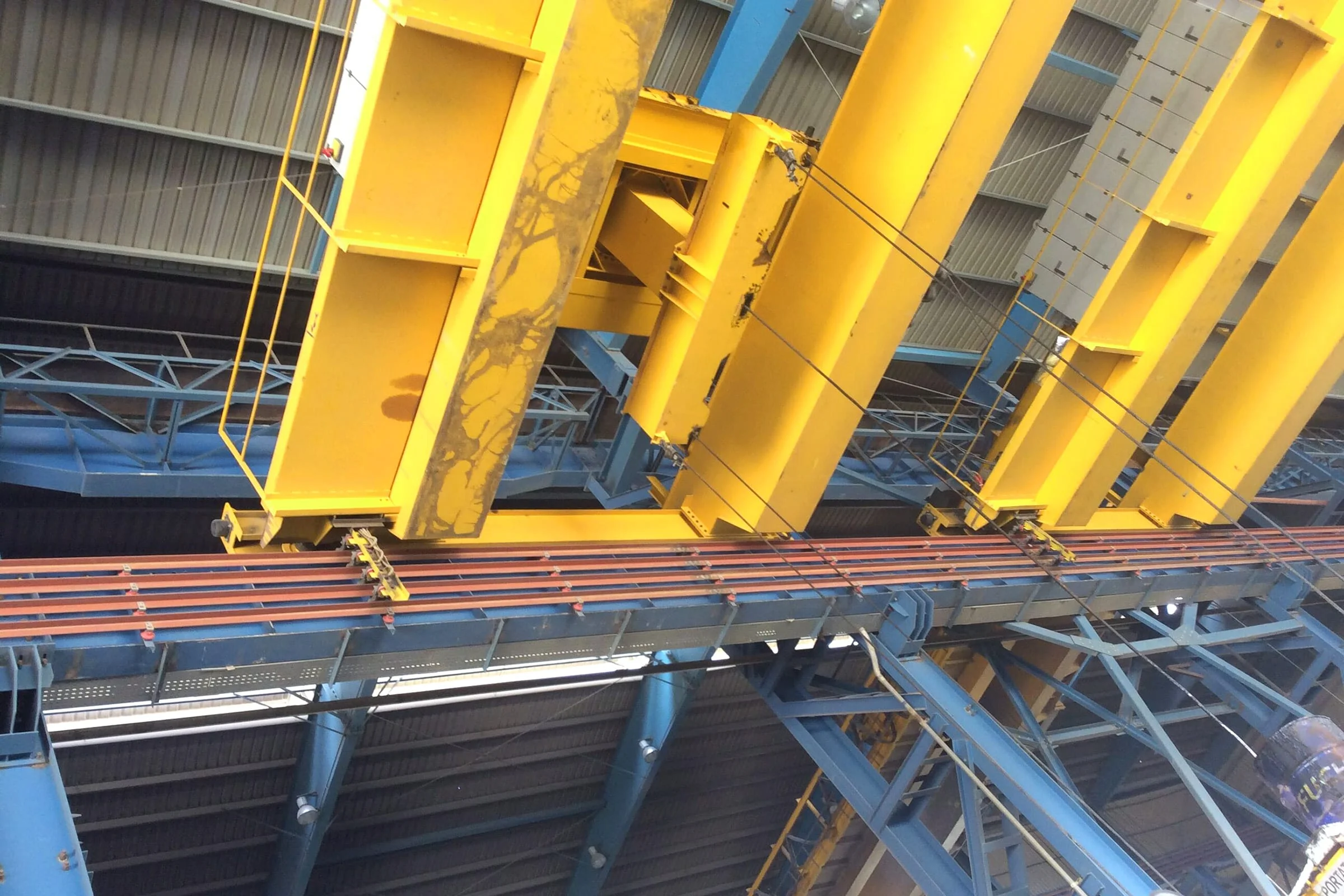 Fixed runway conductors and moving collector assemblies beside overhead crane bridges