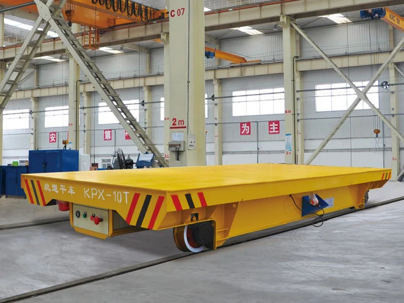 Yellow flat-deck rail transfer cart on two workshop rails