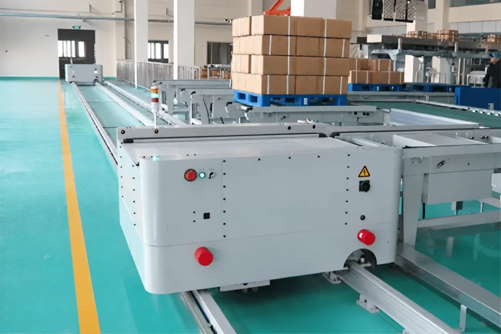 Rail-guided conveyor vehicle aligned with fixed pallet conveyors in a warehouse