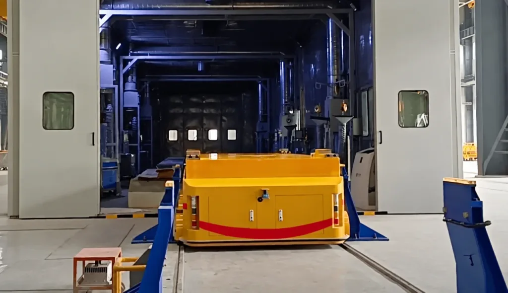 Yellow rail vehicle aligned with rails through an industrial equipment doorway