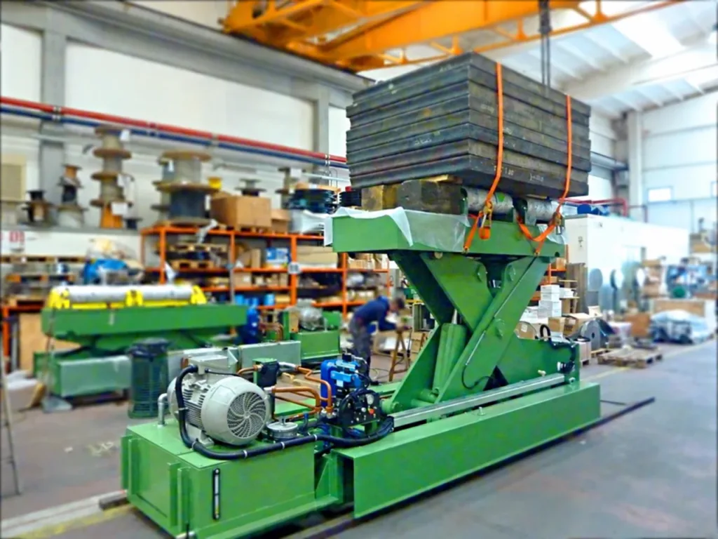 Lifting coil car carrying steel slab test weights on an elevated saddle with hydraulic equipment visible