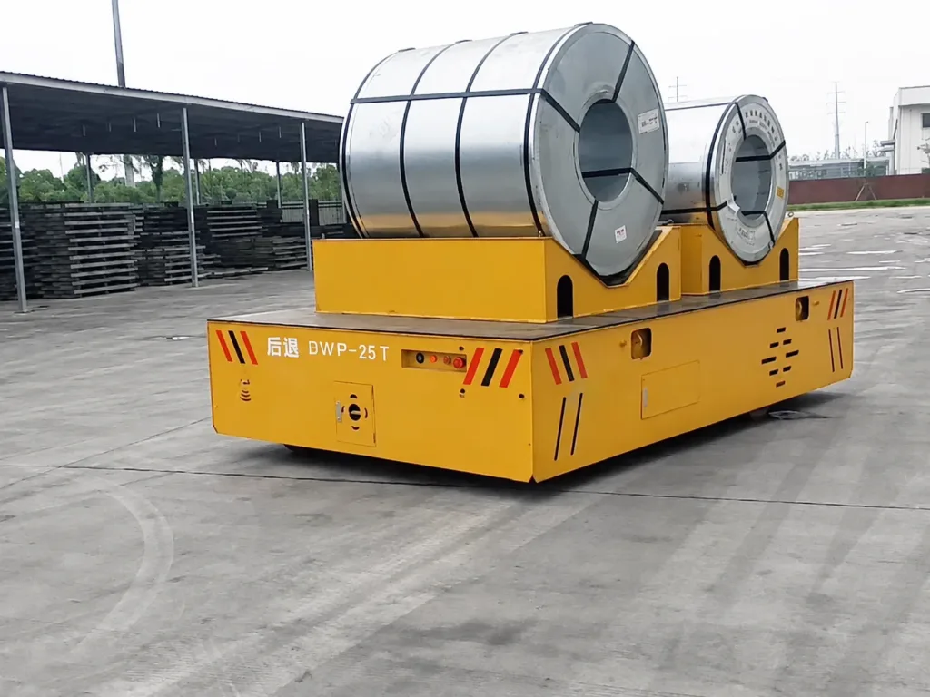 Two steel coils in shaped saddles on a yellow trackless transfer cart