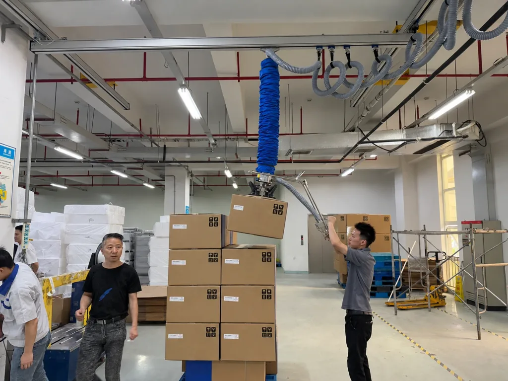 Vacuum tube lifter handling a carton at a workstation